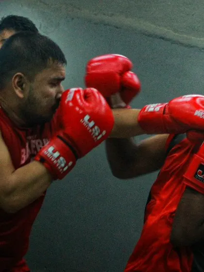 Two boxers in red trading blows. This is a classic in fighting scenario, where technique and toughness are both on full display.
