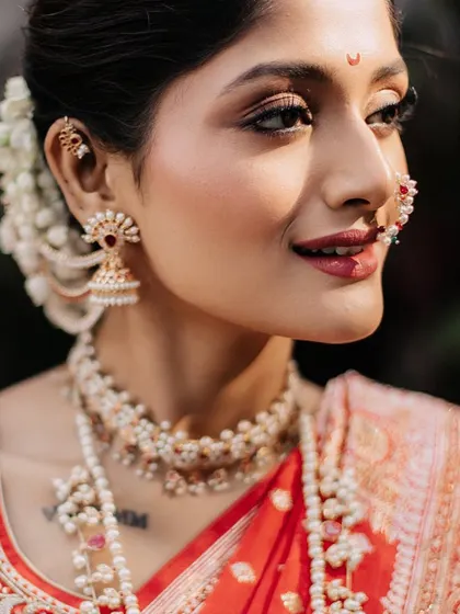 An extreme close-up of the bride, highlighting her flawless makeup, traditional bindi, and pearl jewelry.