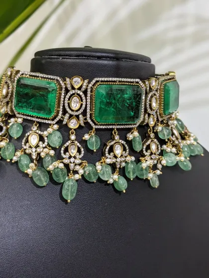 A macro shot of the choker, detailing the large emerald-colored stones and surrounding polki-style work.