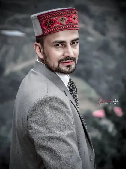 A classic groom's portrait in a grey suit and traditional Himachali cap. The desaturated color palette gives this photo a sophisticated and timeless feel.