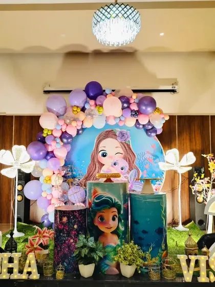 Another angle of the dual mermaid birthday party, showing the full arrangement with the character backdrop and floral light props.