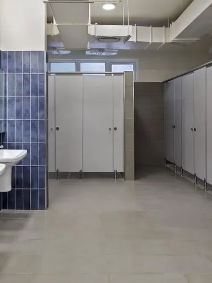 The school bathrooms were updated with durable materials and a clean design. The use of deep blue tiles and modern fixtures creates a hygienic and pleasant environment for students.