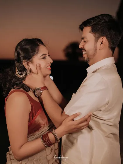 A candid and happy close-up of a couple by the water at dusk, their smiles showing their genuine joy.