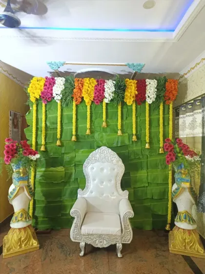 Even a simple setup at home can be beautiful. For this Shreemantha, I created a backdrop using a wall of fresh banana leaves, adorned with colorful flower garlands and a traditional white chair for the ceremony.