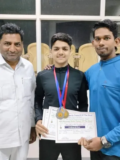 Another photo of my student with his medals from the Haryana State Games, pictured with me and a supporter.