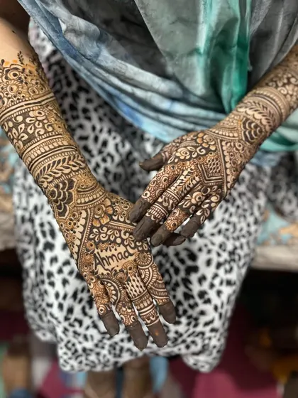An elegant engagement henna design. This style combines traditional bands on the forearm with delicate work on the fingers and the groom's name, Ahmad, on the palm.
