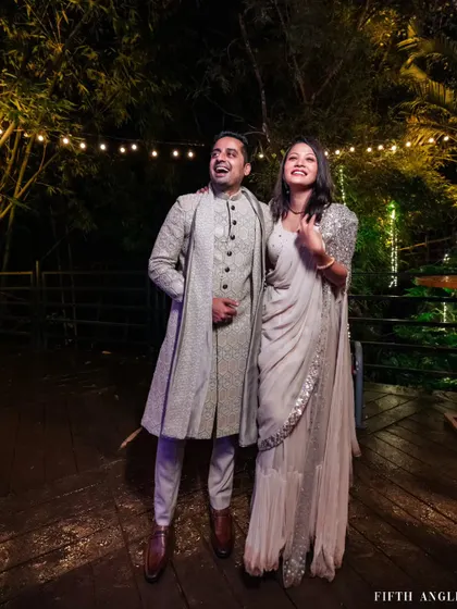 A couple shares a laugh under the warm glow of string lights during their outdoor reception in Coorg.