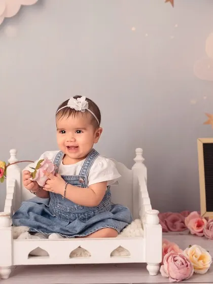 Sitting pretty on a miniature bed surrounded by flowers. Sitter sessions are perfect for using cute props now that your baby can support themselves.