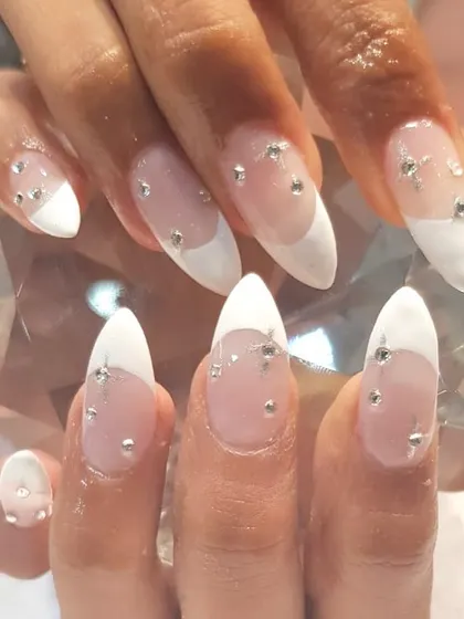 These almond-shaped nail extensions feature a modern French tip and delicate crystal embellishments. This is a popular choice for clients heading on vacation or for brides wanting a touch of sparkle.