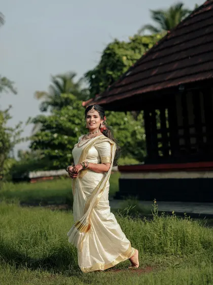 A classic and elegant full-length portrait of the bride in her kasavu saree.