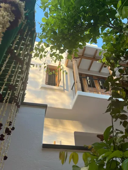 A glimpse of my first project in Mysore, showing a traditional balcony with wooden shutters, seen through lush foliage.