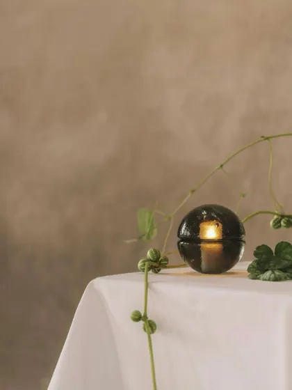 A single smoked grey 14p on a white tablecloth, its simple elegance making it a beautiful object even when unlit.