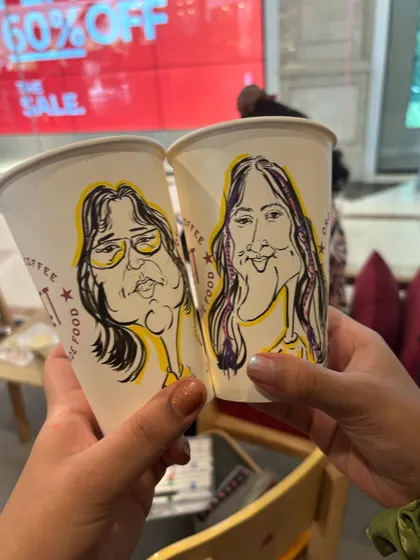 A pair of coffee cups from Pret, each adorned with a custom caricature. A truly unique souvenir.
