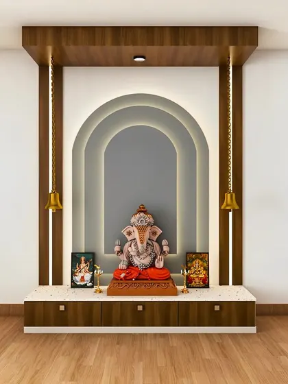 A modern pooja unit with a multi-layered arch design and soft backlighting. The design includes a pedestal for the main idol and hanging brass bells for a traditional touch.