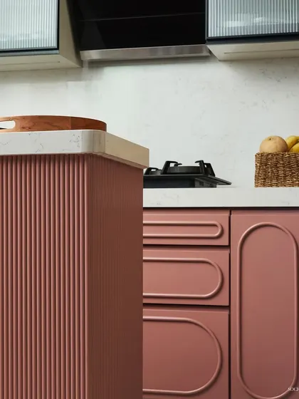A close-up of the kitchen cabinetry, highlighting the combination of fluted panels and smooth, curved drawer fronts. These details add a layer of sophistication and tactile interest to the design.