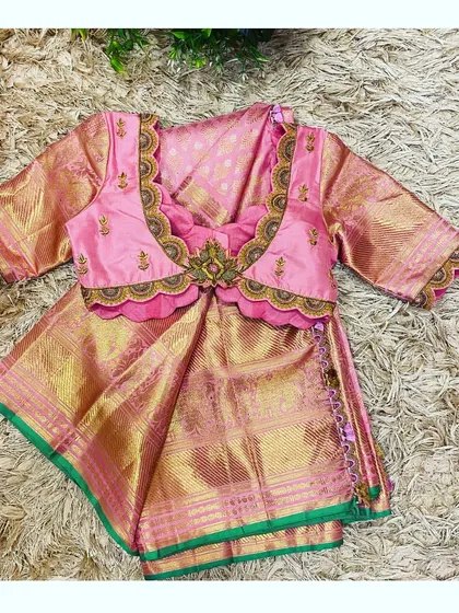 This is a closer look at a custom-designed blouse for a child's Pattu Pavadai, a traditional South Indian outfit. I crafted this piece from rich pink silk with a scalloped neckline and delicate hand embroidery to perfectly match her mother's saree, creating a beautiful and memorable twinning moment.