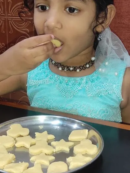 A child tastes the star-shaped cookies she made. When children are involved in the cooking process, they are more open to trying new flavors and textures.