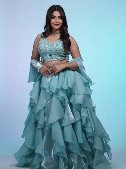 A full-length shot of the ruffled blue lehenga. The layers of organza create a dreamy, cloud-like effect that's absolutely magical.