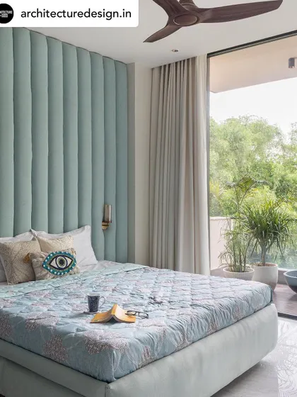 This bedroom, part of a "Haven of Peace" project, features a floor-to-ceiling upholstered headboard in a calming seafoam green. The large glass doors open to a balcony, blurring the line between indoors and outdoors.