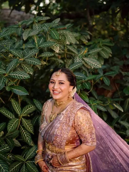 The bride looking radiant and happy, surrounded by the lush greenery of the wedding venue.
