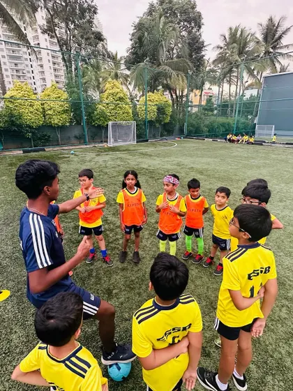 A coach gives a team talk to a group of young players. We teach them to listen, understand strategies, and work together as a cohesive unit.