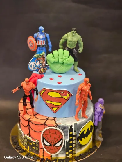 An action-packed two-tier Avengers cake for a young superhero fan. I used a combination of fondant details like the Hulk fist and toy toppers of characters like Captain America, Spider-Man, and Superman to bring the theme to life.