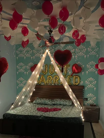 A straight-on view of the 'Just Married' bed decoration, showing the foil balloons, heart-shaped balloons, and the light-up canopy.