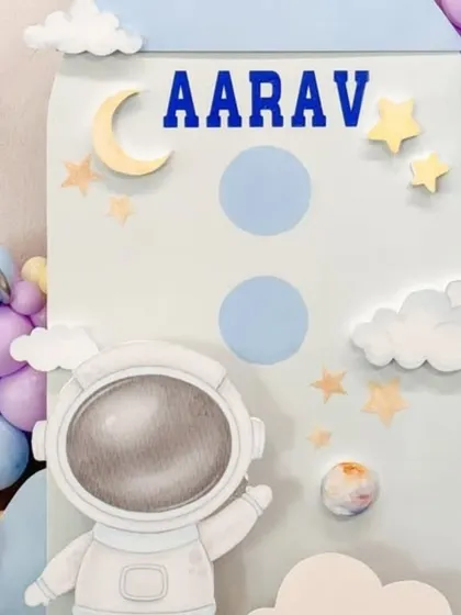 A close-up of the personalized rocket ship backdrop for Aarav's first birthday, featuring his name and cute celestial details.