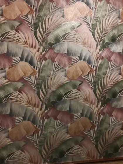 A framed wallpaper panel with a colorful tropical leaf design. The wooden frame gives it a rustic touch and makes the wallpaper feel like a deliberate piece of art.