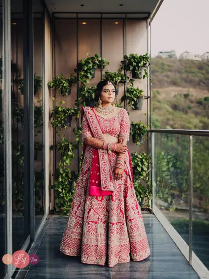 A full-length shot of the bride, Rucha, on the balcony, showcasing her entire bridal look against a scenic view.