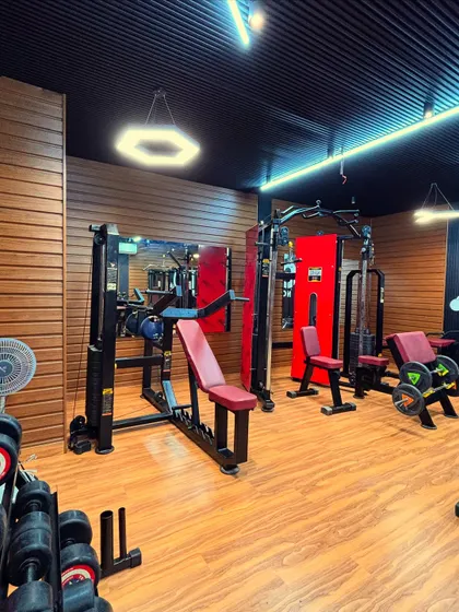 This area is set up for strength training, with multiple machines and a weight rack. We ensure there is enough space around each piece of equipment for safe and effective use. The hexagonal pendant light adds a unique design touch to the space.