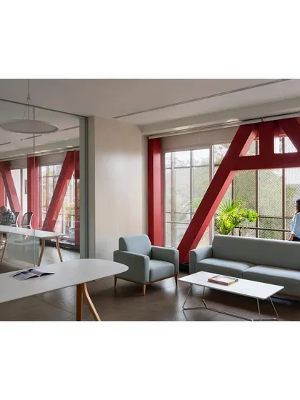 The interior of 'Hoverspace' is a column-free environment where structural trusses are celebrated as sculptural red elements. Minimalist furniture and extensive use of glass for partitions create a transparent, light-filled, and collaborative workspace.