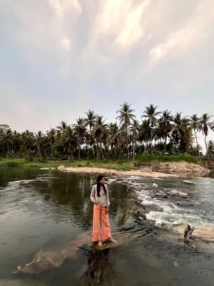 Standing on the rocks in the river, with the wide sky and palm trees creating a stunning panorama.