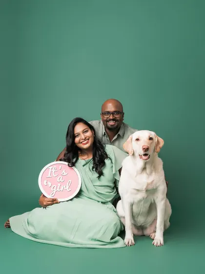 A beautiful family portrait celebrating their upcoming arrival. The "It's a girl" sign adds a lovely touch to this happy family moment.