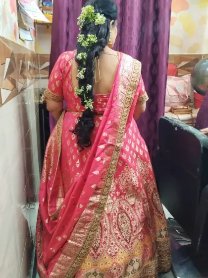 A lovely client dressed in a traditional pink and gold banarasi lehenga for a family wedding. The beautiful floral hairstyle complements the ethnic look perfectly.