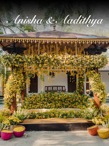 The Haldi ceremony setup for Anisha and Aadithya, designed to be bright, happy, and full of life. The decor is centered around a traditional wooden mandap adorned with yellow flowers.