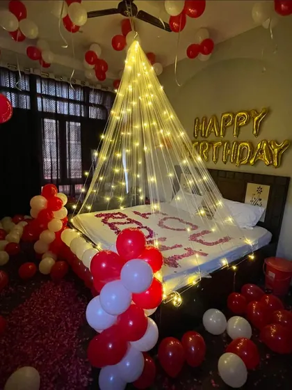 A romantic birthday surprise in the bedroom. I created a cozy atmosphere with a fairy light canopy over the bed, red and white balloons filling the room, and flower petals spelling out "I LOVE YOU" for a truly personal touch.