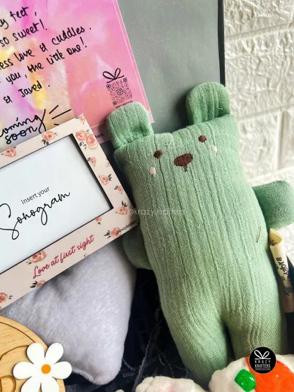 A soft, green teddy bear plushie, a perfect cuddly friend for a newborn, featured in our baby hampers.