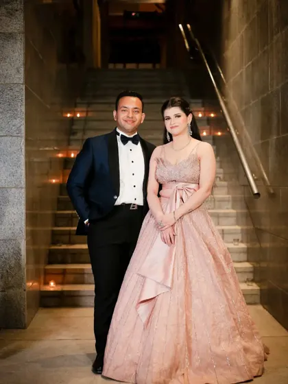 A full-length formal portrait of the couple on their engagement day. Posed on a candlelit staircase, they look like a classic, elegant pair.