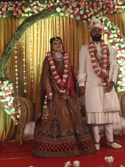 A couple poses on their beautiful reception stage. We work to create the perfect backdrop that not only looks great in person but also makes for stunning wedding photography.