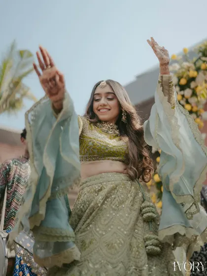 The bride's joyful dance as she enters her Mehendi ceremony. Her flowing sleeves and happy expression create a beautiful sense of movement and celebration.