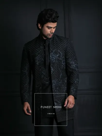 I designed this midnight-black achkan for the man who appreciates understated elegance. The slim, knee-length silhouette features a unique lattice texture and subtle ink-blue ornamental embroidery, creating a modern yet powerful statement for any evening affair.