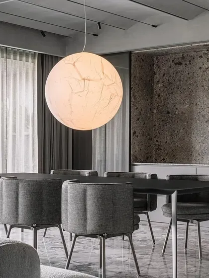 Another perspective of the dining area in the Vaulted Haus, showing how the 'Moon' pendant light interacts with the surrounding grey scale material palette. The light fixture is a key element in establishing a dialogue between the living and dining zones.