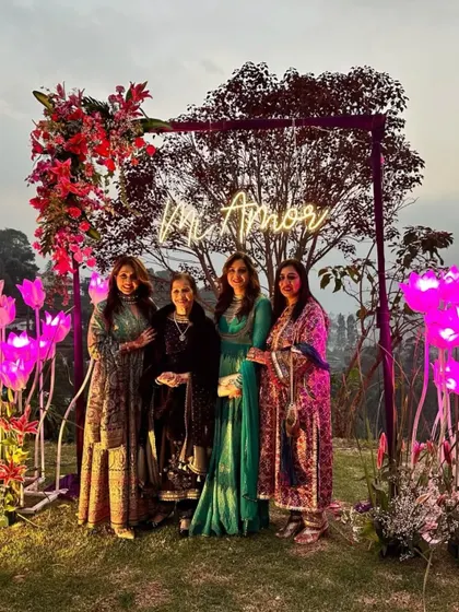 A beautiful photo opportunity at a Sangeet event, featuring a "Mi Amor" neon sign inside a floral arch with illuminated tulips. It provides a perfect spot for guests to capture memories.
