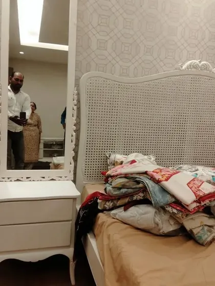 A real-site photo showing the white rattan bed and matching dressing table with a full-length mirror, demonstrating how custom furniture fits perfectly into the client's space.