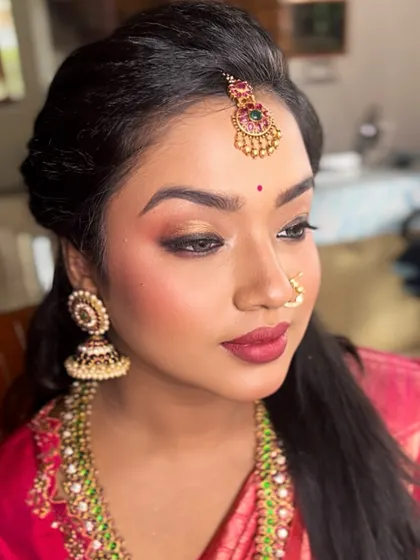This bride's look for her Muhurtham features soft golden eyeshadow to match her jewelry, paired with a beautiful magenta lip that brings out the color of her silk saree.