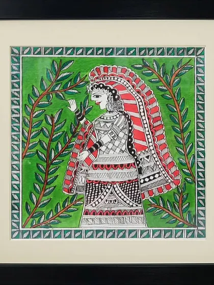 A woman dressed in intricately patterned traditional clothing stands amidst lush greenery in this Madhubani painting by Anu Bansal. The detailed line work on her attire is a highlight of the piece.