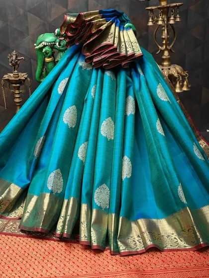 This turquoise Kanjivaram silk saree is a vision of elegance. The body is covered in silver leaf motifs, and the contrasting gold border adds a warm glow. It’s a unique color that is sure to turn heads.