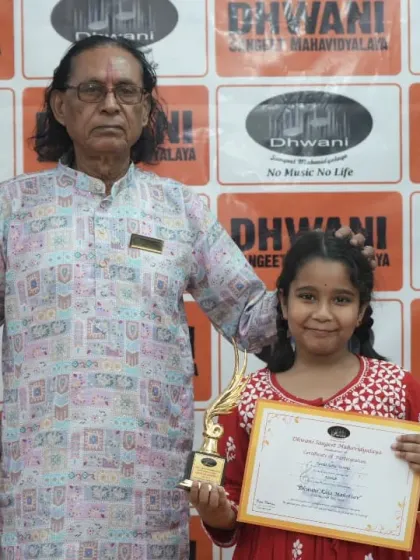 A senior guru with his young student and her award.