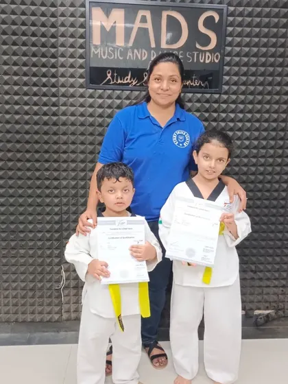 Two young brothers celebrate their taekwondo achievement together, both earning their yellow belts. It's wonderful to see siblings supporting each other on their learning journey.